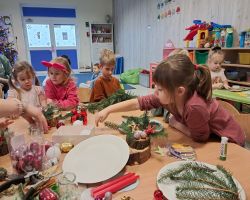 dzieci i rodzice tworzą stroiki podczas warsztatów świątecznych w przedszkolu