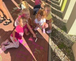 dzieci rysują kredą po chodniku