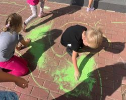 dzieci rysują kredą po chodniku