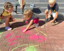 dzieci rysują kredą po chodniku