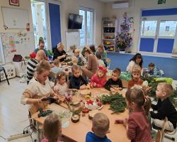 dzieci i rodzice tworzą stroiki podczas warsztatów świątecznych w przedszkolu