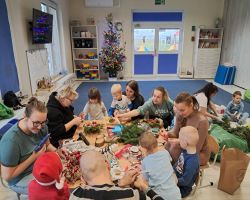 dzieci i rodzice tworzą stroiki podczas warsztatów świątecznych w przedszkolu