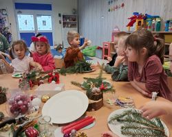 dzieci i rodzice tworzą stroiki podczas warsztatów świątecznych w przedszkolu