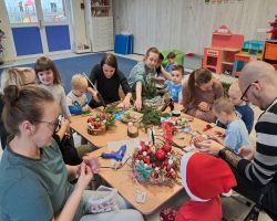 dzieci i rodzice tworzą stroiki podczas warsztatów świątecznych w przedszkolu