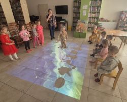 dzieci i bibliotekarka podczas zajęć w bibliotece