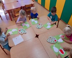 dzieci wykonują pracę plastyczną - malowanie konturu jabłka