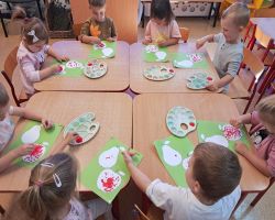 dzieci wykonują pracę plastyczną - malowanie konturu jabłka