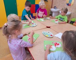 dzieci wykonują pracę plastyczną - malowanie konturu jabłka