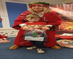 dzieci podczas spotkania ze Świętym Mikołajem i Panią Mikołajową, otrzymują prezenty i śpiewają piosenki