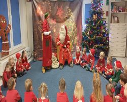 dzieci podczas spotkania ze Świętym Mikołajem i Panią Mikołajową, otrzymują prezenty i śpiewają piosenki