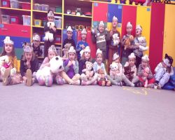 Dzieci uśmiechnięte tańczą z misiami oraz siedzą przy stolikach i kolorują obrazki misiów