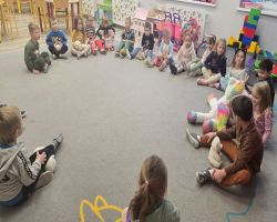 Dzieci uśmiechnięte tańczą z misiami oraz siedzą przy stolikach i kolorują obrazki misiów