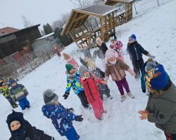 Dzieci bawią się na dworze, jest słoneczne zimowe przedpołudnie