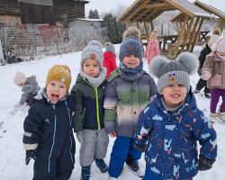 Dzieci bawią się na dworze, jest słoneczne zimowe przedpołudnie