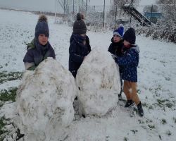 Dzieci bawią się na dworze, jest słoneczne zimowe przedpołudnie