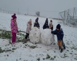 Dzieci bawią się na dworze, jest słoneczne zimowe przedpołudnie