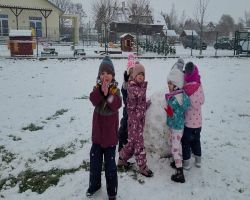 Dzieci bawią się na dworze, jest słoneczne zimowe przedpołudnie