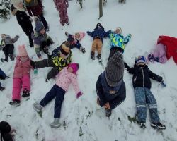 Dzieci bawią się na dworze, jest słoneczne zimowe przedpołudnie