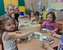 Dzieci ozdabiają wypieczone pierniki kolorowymi posypkami