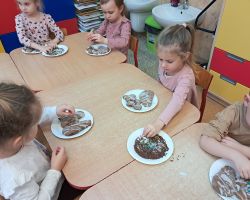 Dzieci ozdabiają wypieczone pierniki kolorowymi posypkami