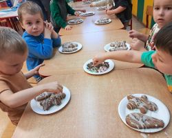 Dzieci ozdabiają wypieczone pierniki kolorowymi posypkami