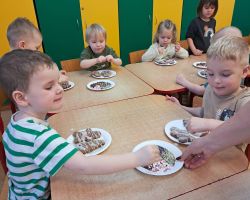 Dzieci ozdabiają wypieczone pierniki kolorowymi posypkami