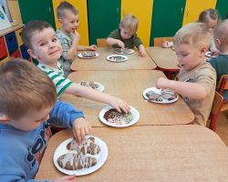 Dzieci ozdabiają wypieczone pierniki kolorowymi posypkami