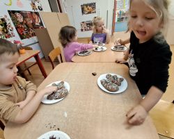 Dzieci ozdabiają wypieczone pierniki kolorowymi posypkami