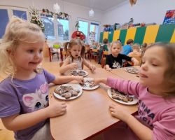 Dzieci ozdabiają wypieczone pierniki kolorowymi posypkami