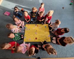 Dzieci ozdabiają plakat kolorowymi kołami origami