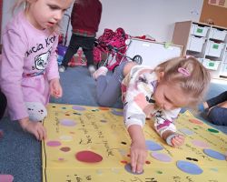 Dzieci ozdabiają plakat kolorowymi kołami origami