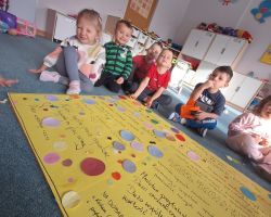 Dzieci ozdabiają plakat kolorowymi kołami origami