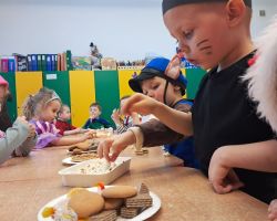 dzieci przebrane za postacie z bajek tancza na balu, pozuja do zdjecia grupowego, jedza poczestunek