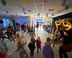 dzieci przebrane za postacie z bajek tancza na balu, pozuja do zdjecia grupowego, jedza poczestunek