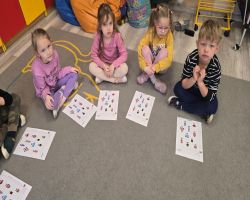 Dzieci siedzą na dywanie w kole i słuchają opowiadania.