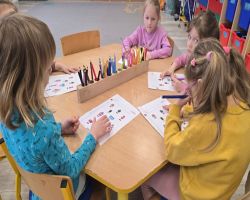 Dzieci siedzą na dywanie w kole i słuchają opowiadania.