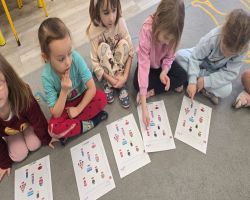 Dzieci siedzą na dywanie w kole i słuchają opowiadania.