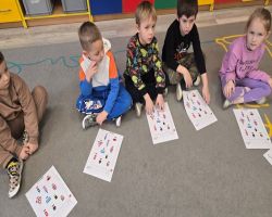 Dzieci siedzą na dywanie w kole i słuchają opowiadania.