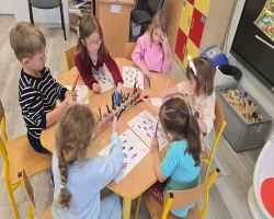 Dzieci siedzą na dywanie w kole i słuchają opowiadania.