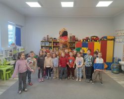 Dzieci świętują Dzień Dinozaura. Siedzą razem na dywanie i tworzą makietę.