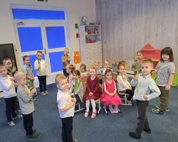 dzieci świętują Dzień Kobiet i Dziewczynek chłopcy składają życzenia i wręczają kwiaty