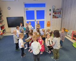 dzieci świętują Dzień Kobiet i Dziewczynek chłopcy składają życzenia i wręczają kwiaty