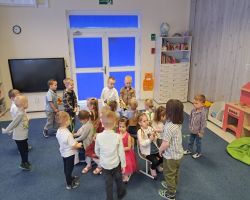 dzieci świętują Dzień Kobiet i Dziewczynek chłopcy składają życzenia i wręczają kwiaty