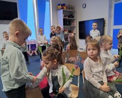 dzieci świętują Dzień Kobiet i Dziewczynek chłopcy składają życzenia i wręczają kwiaty