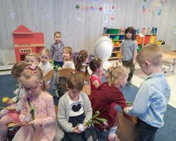dzieci świętują Dzień Kobiet i Dziewczynek chłopcy składają życzenia i wręczają kwiaty