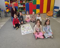 Dzieci siedzą na dywanie i prezentują swoje ulubione książki