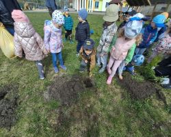 Przedszkolaki tworzą kreatywne prace plastyczne przy stolikach, a następnie sadzą drzewa w ogrodzie.