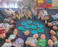 Przedszkolaki tworzą kreatywne prace plastyczne przy stolikach, a następnie sadzą drzewa w ogrodzie.